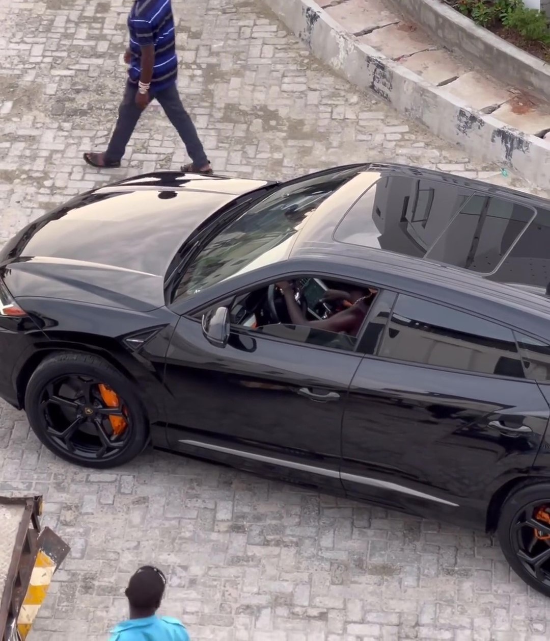 Seyi Vibez sitting inside his Lamborghini Urus SUV